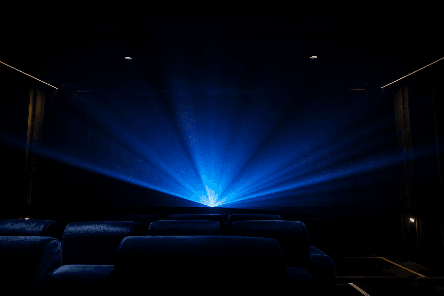 Salle de projection dans la pénombre, faisceau de lumière bleue.