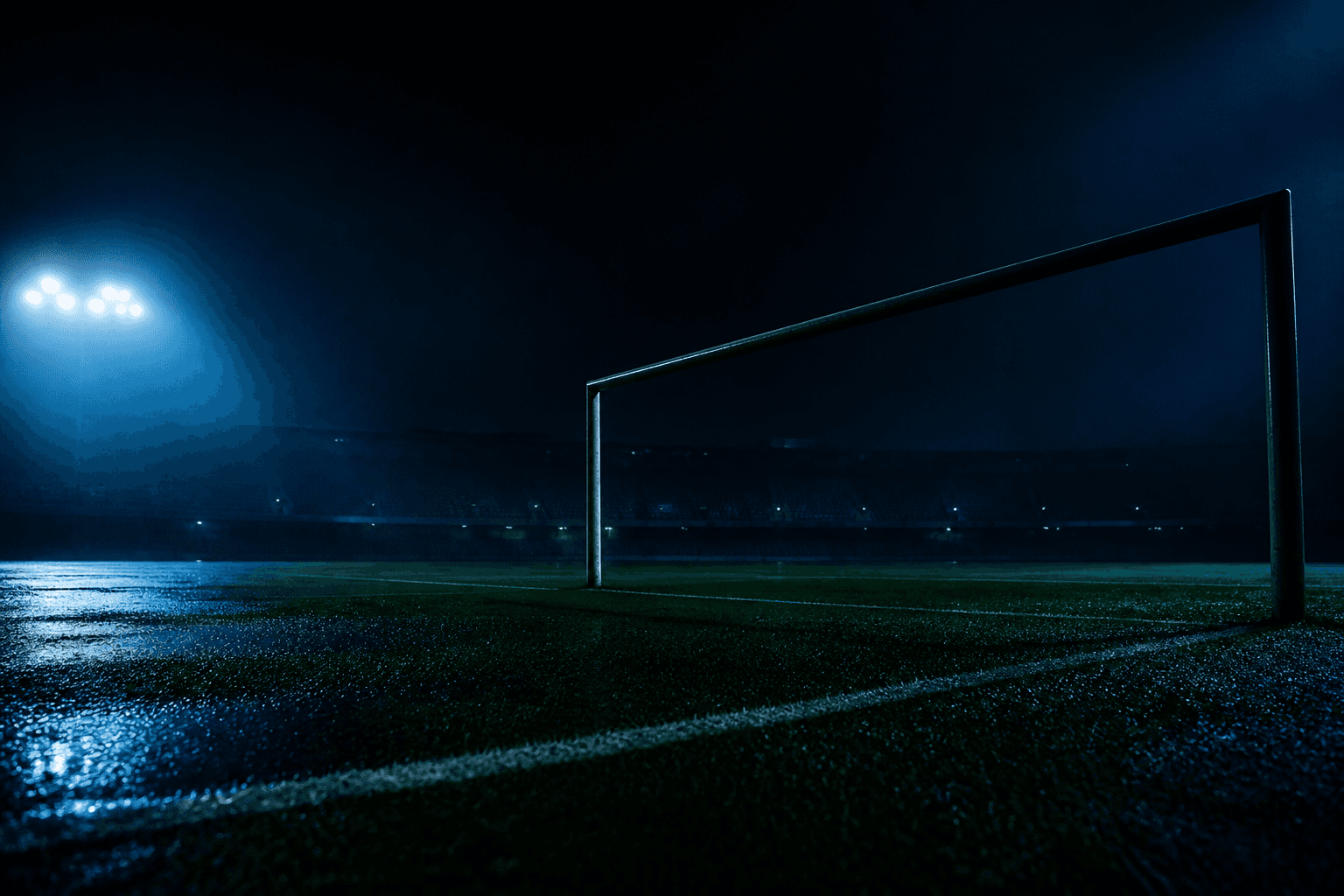 Pelouse de football sous les projecteurs, cadre de but sans logo.