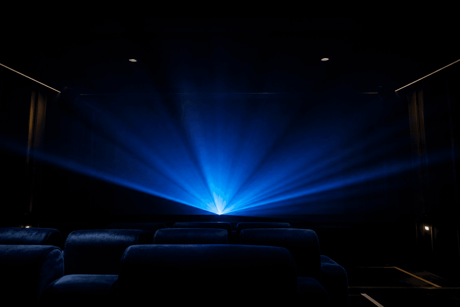 Salle de projection dans la pénombre, faisceau de lumière bleue.